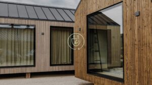 Modern wood-clad modular homes with large windows and energy efficiency icon, showcasing are modular homes energy efficient with sustainable design features.