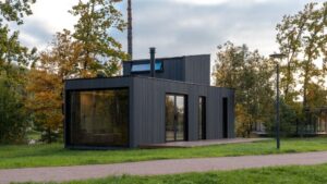 Modern black modular home with large windows in a wooded setting, illustrating how long do modular homes last with durable factory-built construction.