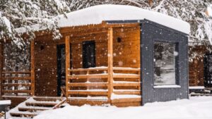 odern modular home with wood and metal exterior in snowy forest, demonstrating cold-climate performance and insulation effectiveness in winter conditions
